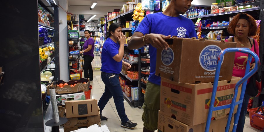 Een man tilt dozen van een steekwagen in een supermarkt